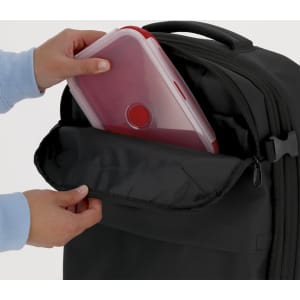 A black lunch box with a clear container is being placed into a zipped compartment by a person’s hands.