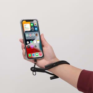 A black charging cable with a holder attached to a hand, supporting a smartphone displaying various apps.