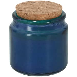 A blue aromatic candle in a glass jar with a cork lid. The jar features a smooth, glossy finish.