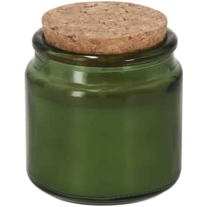 A green aromatic candle in a glass jar with a cork lid.