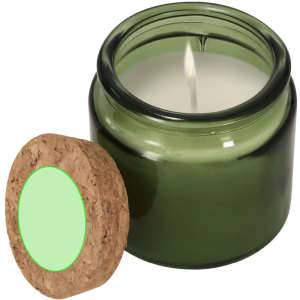 A green aromatic candle in a glass jar with a cork lid, featuring a white wax interior.