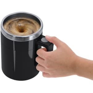 A mixing mug in black with a silver rim, featuring a handle, being held by a hand.