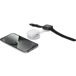 A wireless charger in black and silver, charging a smartphone, earbuds, and a smartwatch. The charger features a logo.