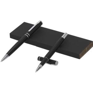 A set of two black metal pens with silver accents resting on a black box. The box is partially visible.