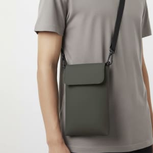 A grey multipurpose bag with a strap, worn on a person's shoulder, featuring a simple design and a clasp closure.