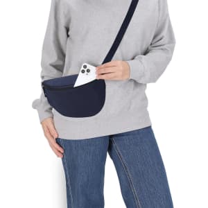 A navy waist bag is being worn, with a smartphone partially visible inside. The model is dressed in a grey sweatshirt and jeans.