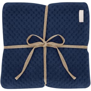 A navy blue Iridian blanket tied with a natural rope, featuring a textured design. It has a small logo or branding.