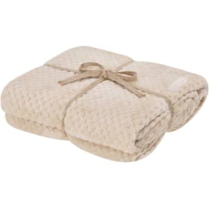 A beige Iridian Blanket neatly folded and tied with a natural rope. The blanket features a textured surface.