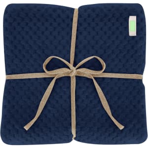 A navy blue blanket folded neatly and tied with a natural twine ribbon, featuring a small logo.