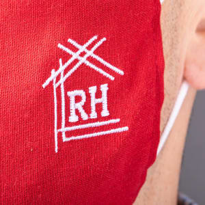 A red reusable hygienic mask with a white logo on the side.