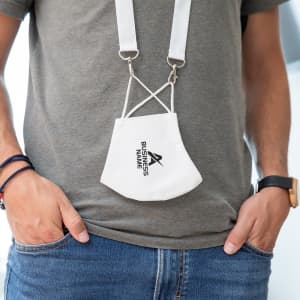 A white lanyard hangs from the neck of a person, featuring a pouch with a logo. The person is casually dressed in a grey shirt and jeans.