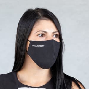 A black reusable hygienic mask worn by a woman, featuring branding on the side.