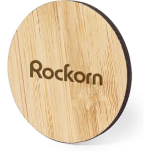 A round wooden coaster with a natural finish and a dark edge, featuring a brand logo.
