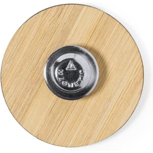 A circular lapel pin with a wooden surface and a shiny, chrome magnet at the centre.