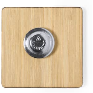 A lapel pin featuring a silver circular centre attached to a square wooden base.