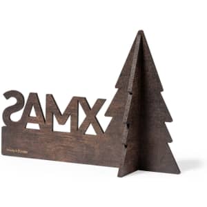 A wooden Christmas decoration featuring the word "Merry" and a tree silhouette, in a brown finish.