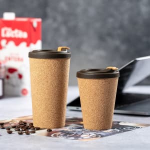 A drink bottle in cork finish with black lids, featuring two sizes on a table with scattered coffee beans.