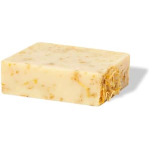 A rectangular bar of yellowish soap with embedded floral pieces, resting on a light surface.