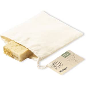 A solid soap bar in a natural fabric pouch, featuring a light beige colour with herbal inclusions.