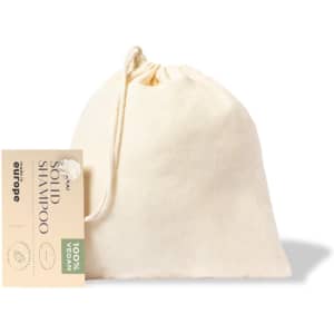 A cream-coloured drawstring bag containing solid shampoo. The bag features a branding label.