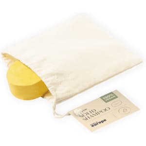A yellow shampoo bar packaged in a cream drawstring bag, featuring a brand label.