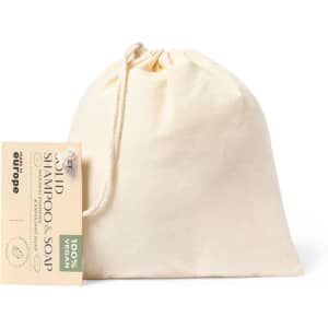 A natural cotton pouch containing solid shampoo and soap, featuring a tag and a logo.
