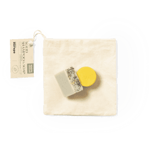 A set of two soap bars, one white with herbs and one yellow, packaged in a natural cotton pouch.