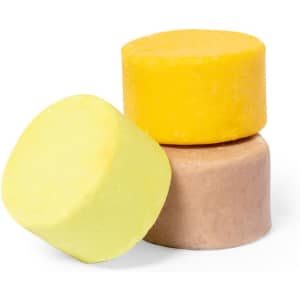 Three solid shampoo bars in yellow and beige colours, stacked in a pyramid formation. Each bar has a smooth texture.