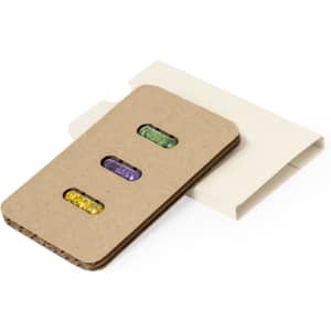 Seed capsules in a kraft paper case, featuring vibrant green, purple, and yellow seeds, placed in a light-coloured sleeve.