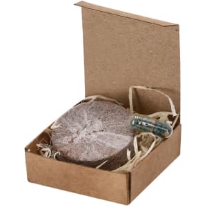 A box containing a round plantable seed disc and a small capsule, with shredded paper filling. The box is brown.