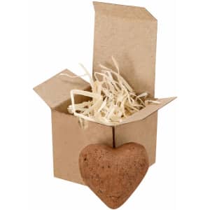 A gold box with an open lid contains shredded paper and a heart-shaped chocolate bonbon.