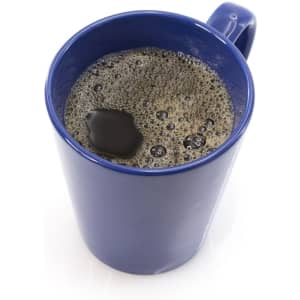 A blue coffee mug filled with dark coffee, featuring bubbles and a glossy surface.
