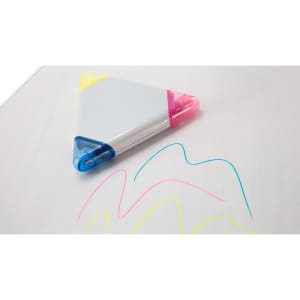 A triangular highlighter with yellow, pink, and blue tips lies on a white surface, alongside colourful ink lines.