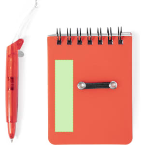 A red mini notebook with a green rectangular section and a spiral binding, accompanied by a transparent red pen.