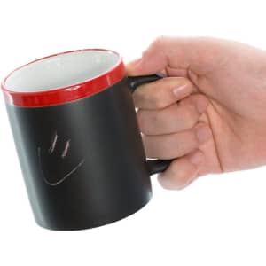 A coffee mug with a matte black exterior and a red rim, held in a hand. It features a simple logo.