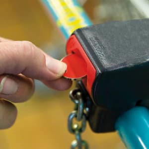 A hand inserting a red coin into a black keyring holder. The holder is attached to a chain.