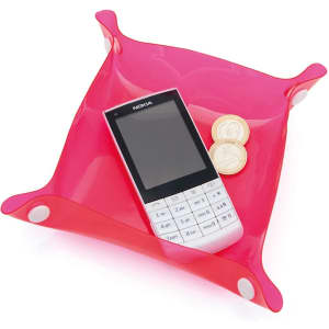 A pink Flot Coin Tray with a mobile phone and two coins placed inside. It features rounded corners and a glossy finish.