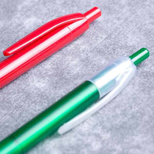 A green and a red plastic pen, both featuring clips and a logo, resting on a grey surface.