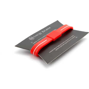 A red Energy Bracelet displayed on a black card, featuring white stripes and a logo.