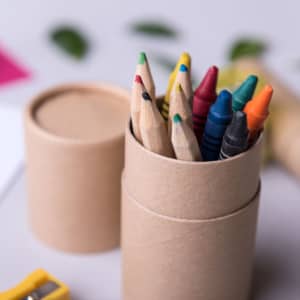 A cylindrical container holding various coloured pencils, including green, red, yellow, and blue, with a sharpener beside it.