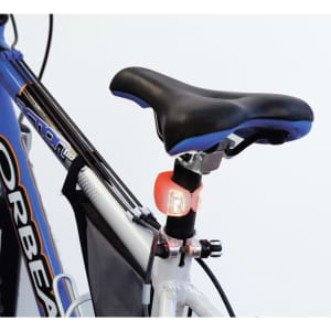 A bicycle seat with a small, pink light attached to the post and a blue and black frame in the background.