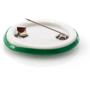 A lapel pin with a green outer edge and a silver fastening on the back. The pin is circular in shape.