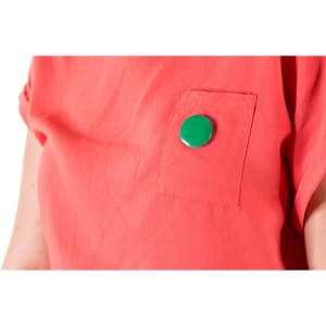 A green lapel pin is attached to a red fabric pocket on a shirt.