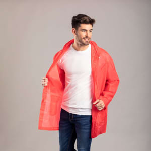 A man wearing a bright red raincoat over a white shirt and jeans, with the coat open and a logo visible.