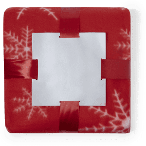 A red blanket featuring a snowflake pattern, secured with red ribbons and a white label in the centre.