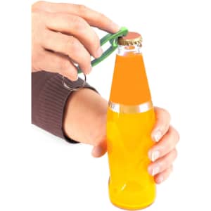 A drink bottle opener keyring in green being used to open a glass bottle of orange beverage.