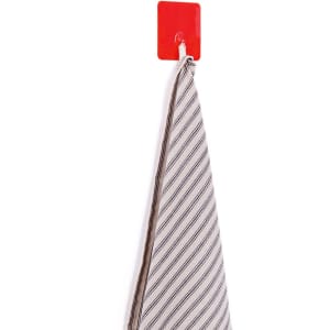 A red multipurpose hook holds a striped fabric item against a wall. The hook has a smooth surface and a simple design.
