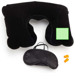 A black travel neck pillow, sleep mask, and earplugs arranged together in a set.