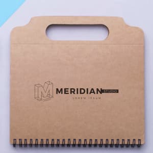 A brown cardboard notepad with a handle, featuring a wire spiral binding and a logo on the front.
