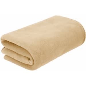 A folded Menex blanket in a soft beige colour, featuring a smooth, plush texture. It has a simple design and a branding logo.